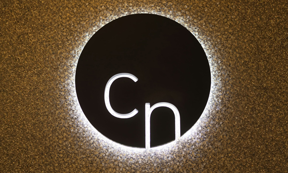 Hinterleuchtetes Cn-Logo auf goldener Mosaikwand
