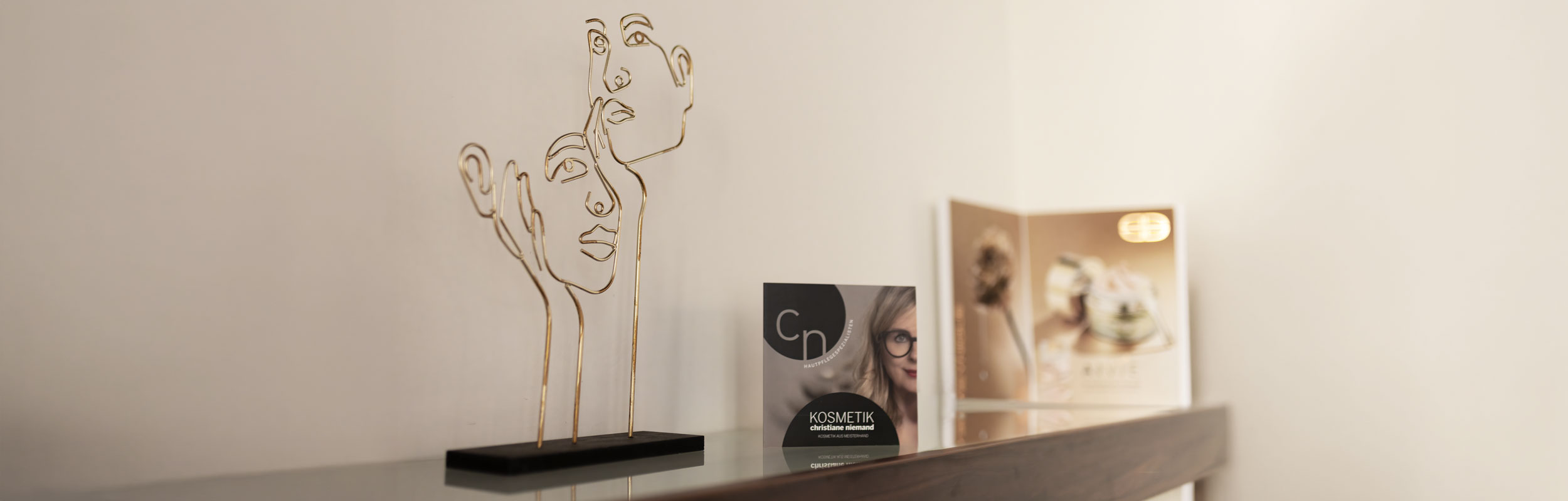 Regal mit goldener Gesichtsskulptur und Infomaterial im Institut